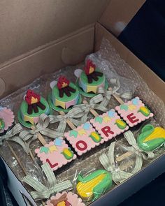 a box filled with lots of decorated cupcakes in the shape of letters and flowers