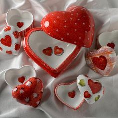 red and white heart shaped dishes with hearts on them, sitting on a white cloth