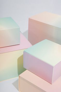 three different colored boxes sitting next to each other on a white surface, one is pink and the other is green