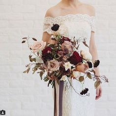 a woman holding a bouquet of flowers in her hand and wearing an off the shoulder dress