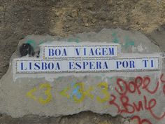 graffiti on the side of a stone wall with two street signs attached to it and another sign that says, boa viagem lisboa espera espea por ti