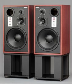 two speakers sitting on top of each other in front of a gray background with red trim