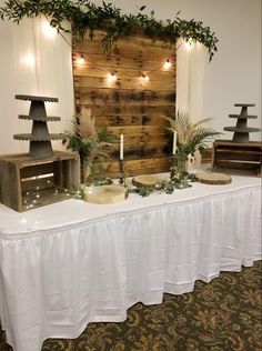 a table topped with lots of food next to a wooden wall covered in greenery