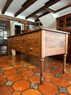 a wooden dresser sitting in the middle of a room with tile flooring and exposed beams