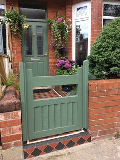 a brick house with a green gate and flower boxes