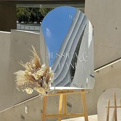 a mirror sitting on top of a wooden easel next to a plant and building