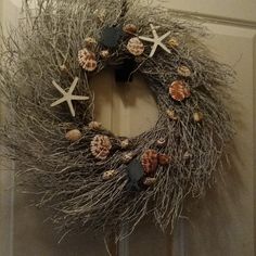 a wreath with starfishs and seashells hanging on the front door handle