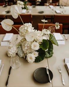 the table is set with white flowers and silverware