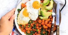 two eggs are on top of carrots, avocado and spinach in a bowl