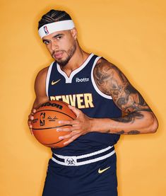 a man holding a basketball in his right hand and wearing a headband with tattoos on it