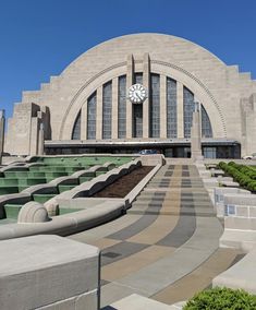 a large building with a clock on it's face in front of some steps