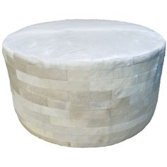 a round ottoman made out of white bricks