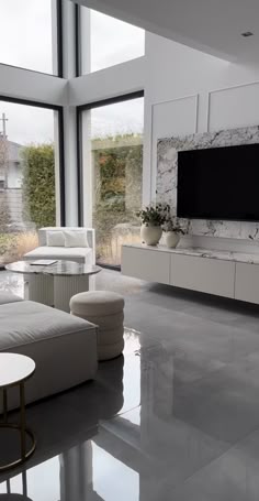 a modern living room with large windows and white furniture in the center, along with a flat screen tv on the wall