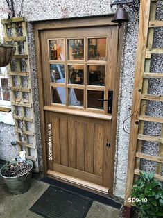 a wooden door with glass panes on the side of a building next to potted plants