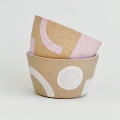 three ceramic bowls are stacked on top of each other, one has pink and white polka dots