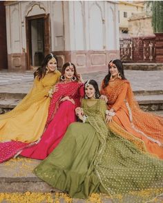 four women in long dresses posing for a photo on the steps with their arms around each other