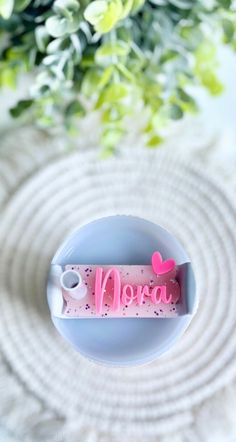 there is a small pink object on top of a white plate with flowers in the background