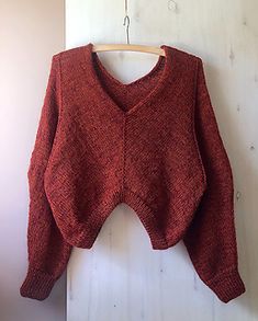 a red sweater hanging on a wooden hanger