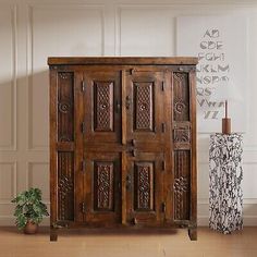 an old wooden cabinet sitting on top of a floor next to a potted plant