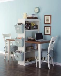 a room with a desk, chair and computer on it in front of a blue wall