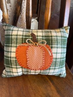 an orange pumpkin pillow sitting on top of a wooden chair