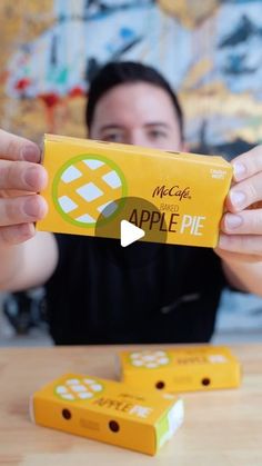 a woman holding up an apple pie box