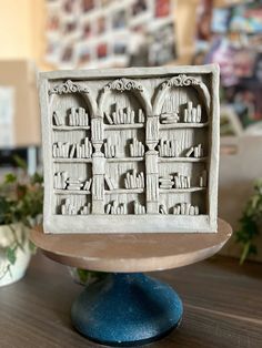 an intricately carved book shelf sits on top of a wooden table in front of some potted plants