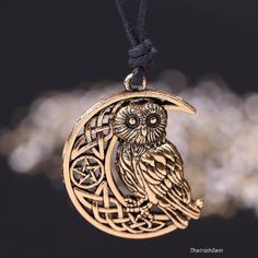 an owl sitting on top of a crescent shaped pendant with celtic symbols in the middle