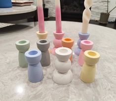 several different colored candles sitting on top of a white table next to a fire place