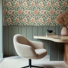 a chair and table in front of a wallpapered room with flowers on it