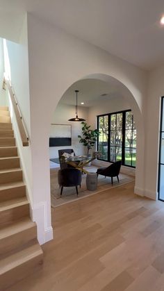 an empty living room with stairs leading up to the second floor and glass doors on both sides