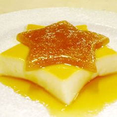 some kind of dessert on a white plate with orange jelly and sugar toppings in the middle