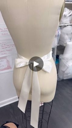 a mannequin with a white bow on it's head and another dummy in the background