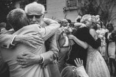 two people hugging each other in the middle of a group of people standing around them