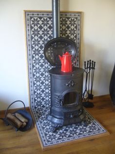 an old fashioned stove sitting on top of a wooden floor next to a tile wall