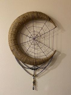 a woven dream catcher hangs on the wall next to a beaded necklace hanging from it's side