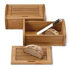 three wooden trays with bread in them on a white surface, one has a knife and the other has a loaf of bread