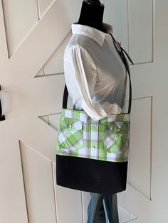 a green and white bag sitting on top of a mannequin