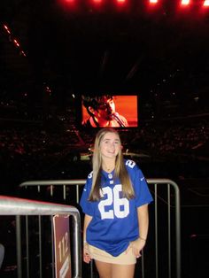 a woman in a football jersey posing for a photo at a stadium with the lights on