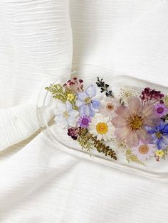 a tray with flowers in it on top of a white cloth covered tablecloths