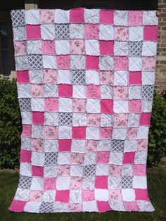 a pink and white quilt hanging from the side of a building