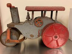 an old metal toy train sitting on top of a silver table next to a white wall