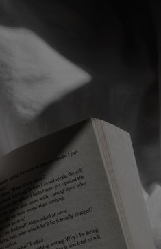 an open book sitting on top of a bed next to a white pillow and blanket