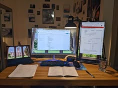 two computer monitors sitting on top of a wooden desk