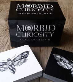 two cards sitting on top of a table next to a box with a moth design