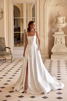 a woman in a white wedding dress standing on a tiled floor with her legs crossed