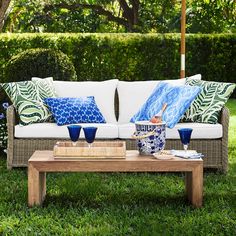 a couch sitting on top of a lush green field next to a wooden coffee table