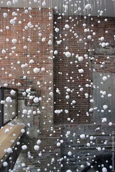 snow is falling from the roof of a building in front of a brick wall and window