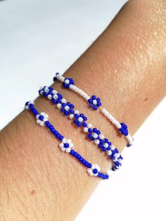 a woman's arm with three blue and white bracelets on top of it