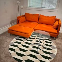 an orange couch sitting on top of a rug in a living room